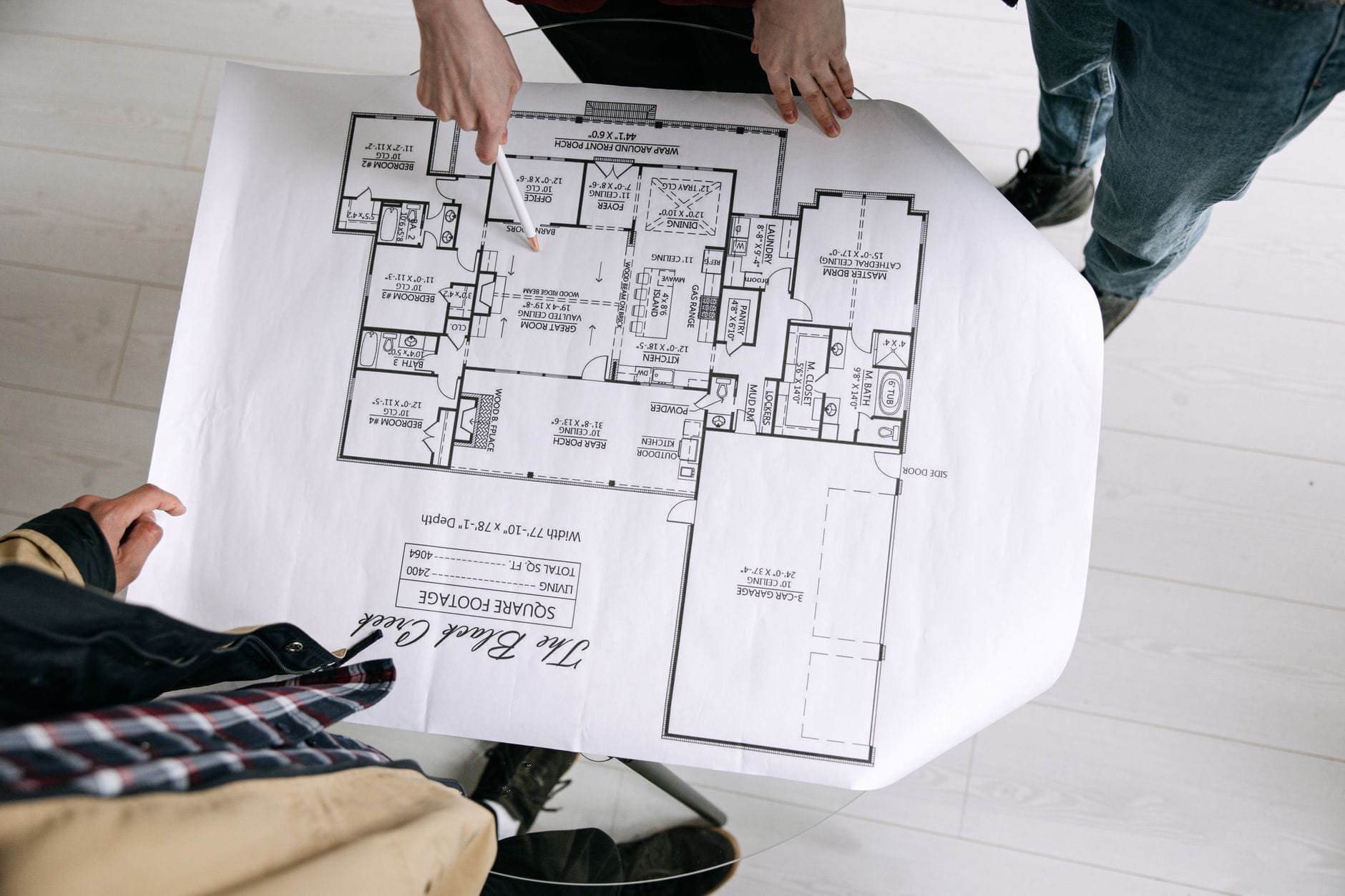 Dwóch architektów analizuje szczegółowy rzut domu na stole