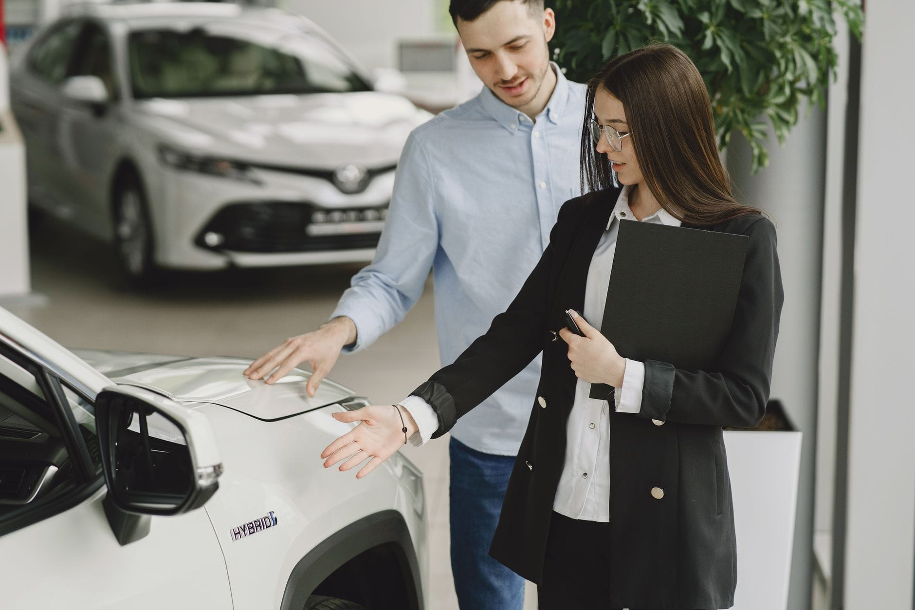 Jak bezpiecznie kupić używane auto hybrydowe: na co zwrócić uwagę przed podpisaniem umowy Mężczyzna z doradczynią omawiający parametry hybrydy w salonie