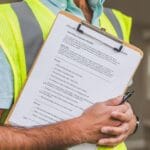 Inspektor domu trzyma checklistę na podkładce i długopis